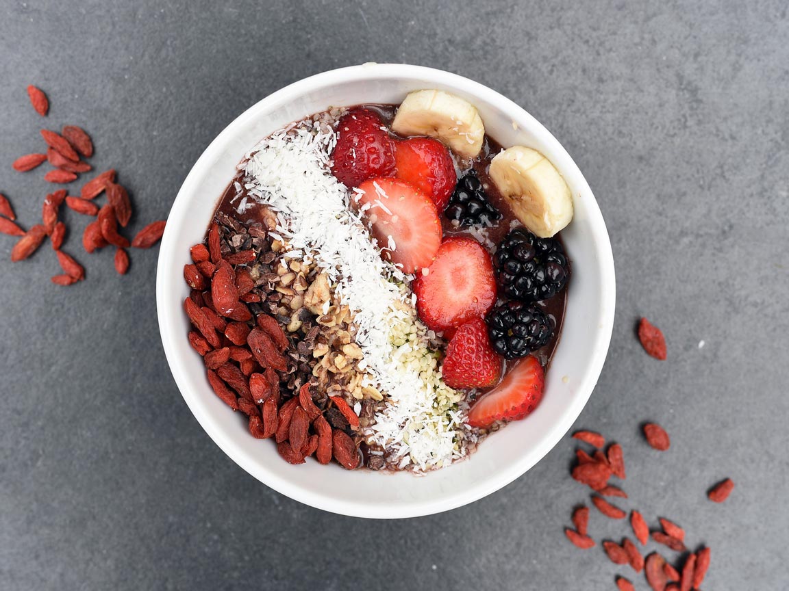 Bowl of cereal with berries, banana, coconut, and nuts